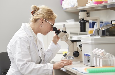 Dr. Percec looking at specimen under microscope.